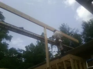 Carpenter setting a ridge beam over a new addition frame — Ice Dam Removal by Roofing Brothers in Wilsons