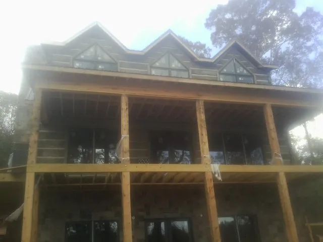 Dormers and porch framing on a large log home under construction — Roof Coating work by our crew in Wilsons