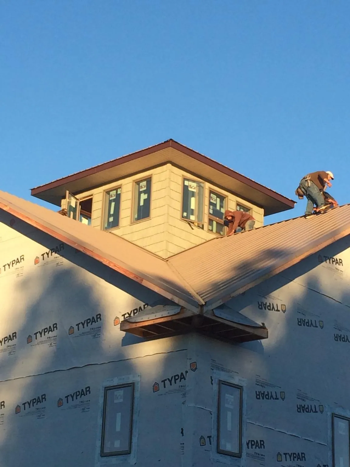 Roofers working around a rooftop cupola on a new metal roof at sunset — Roof Waterproofing in Wilsons by Roofing Brothers